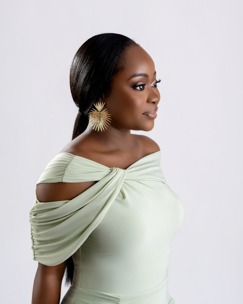 Close-up portrait of a woman in a light green off-shoulder dress with bold earrings, showcasing elegance and confidence.